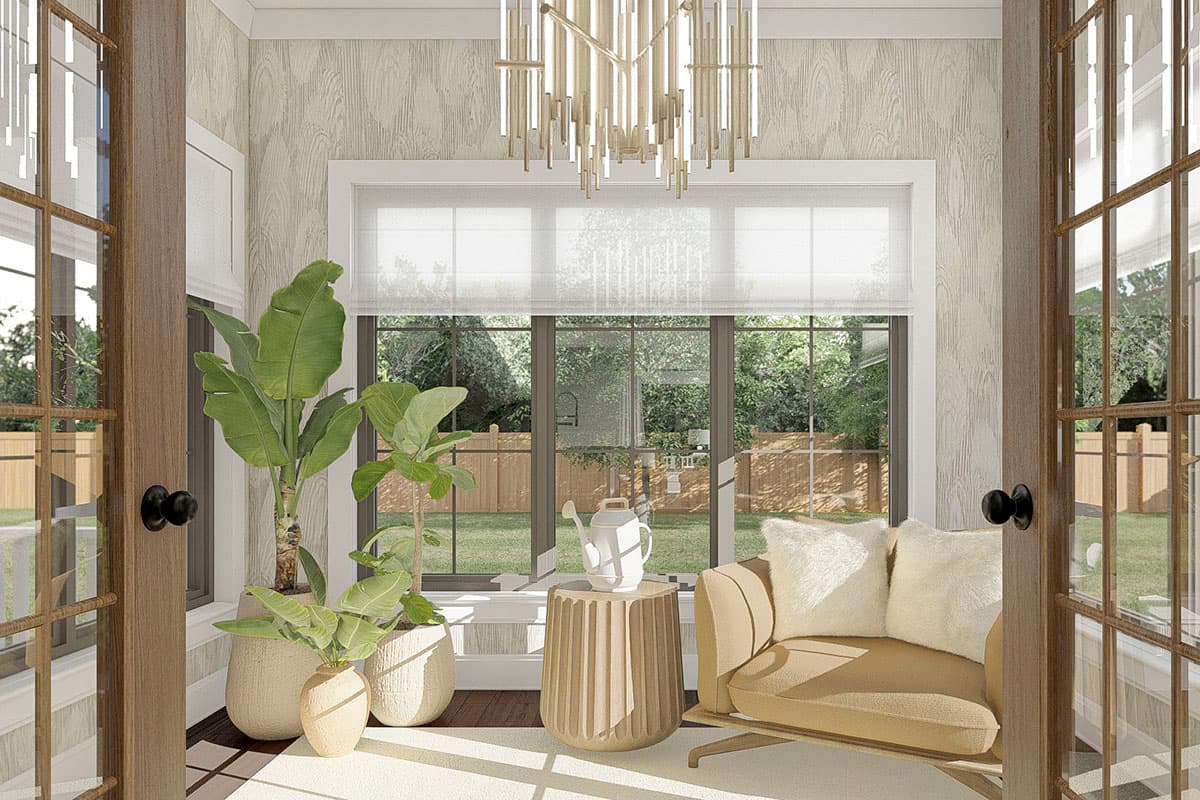 Sunroom interior with large windows, plants, and seating area overlooking a backyard with a wooden fence.