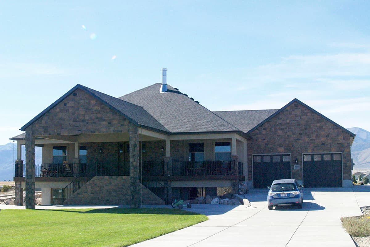House plan exterior, one-story Modern design with stone accents, covered porch, and a three-car garage.