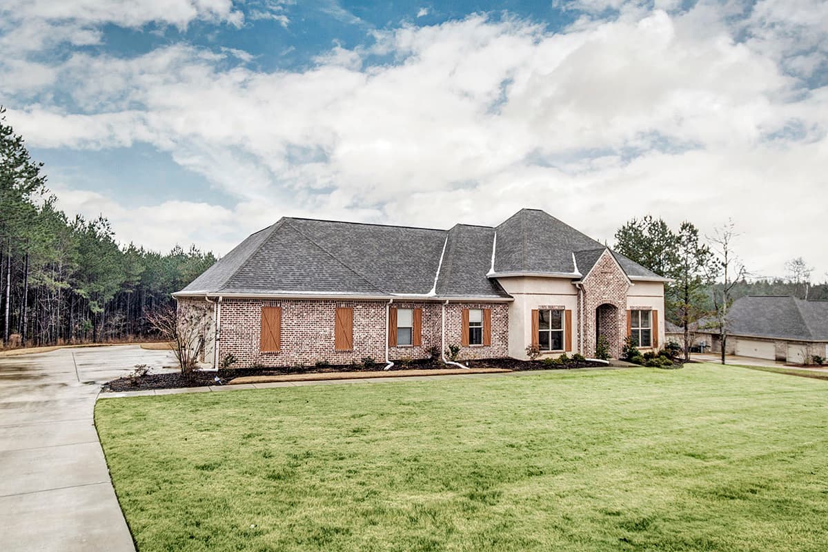 House plan exterior: One-story brick home with arched entryway, gable dormers, and attached garage.