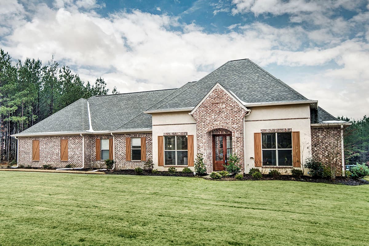 House plan exterior: One-story home with brick and stucco facade, prominent gable, arched entry, and X-braced shutters.