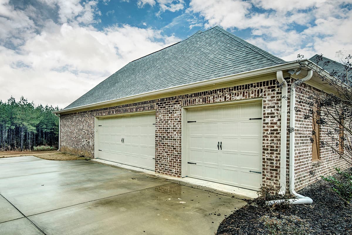 House plan exterior of a brick garage with two white doors, a gambrel roof, and white gutters.