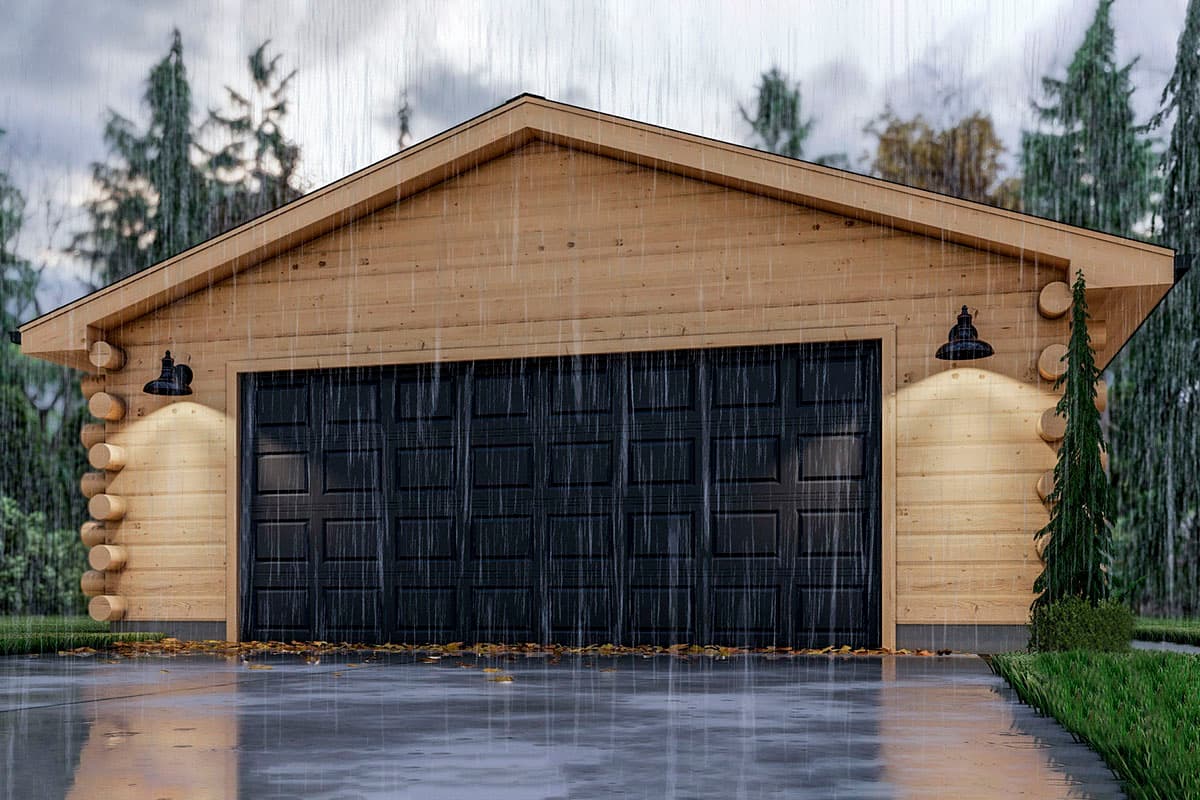 Log home exterior with a wide black garage door, two wall-mounted barn lights, and a gable roof.