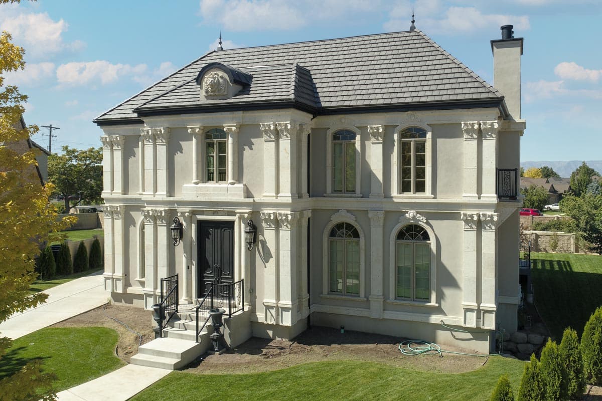 Two-story house plan exterior featuring a stone facade, arched windows, decorative corbels, a dark shingle roof, and a front entry porch with steps.