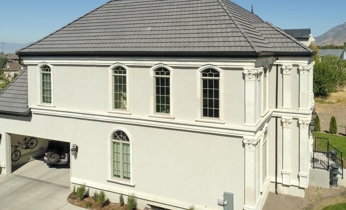 House plan exterior with arched windows, pilasters, and a three-car garage.