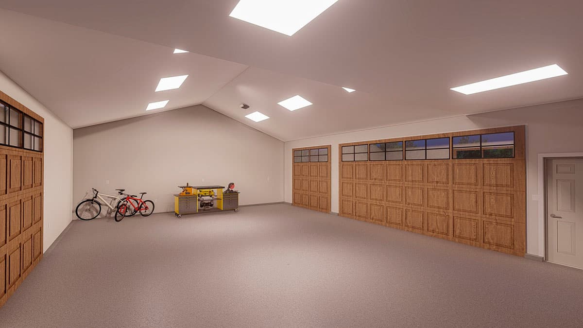 Interior view of a spacious garage with vaulted ceiling, skylights, two wooden garage doors with windows above, and a workshop area with bicycles.