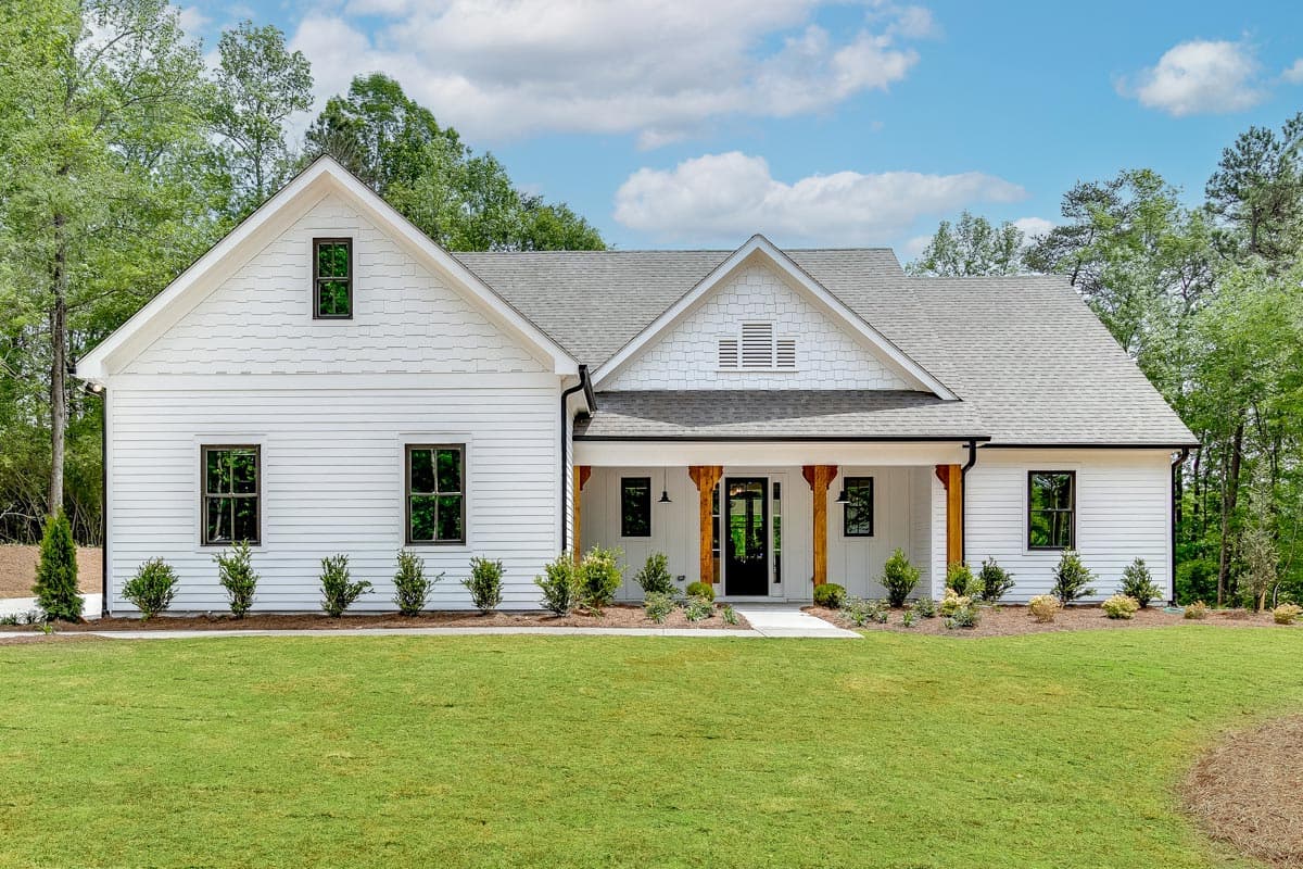 Modern Farmhouse style house plan exterior with gables, wide porch with timber supports, and multiple windows.