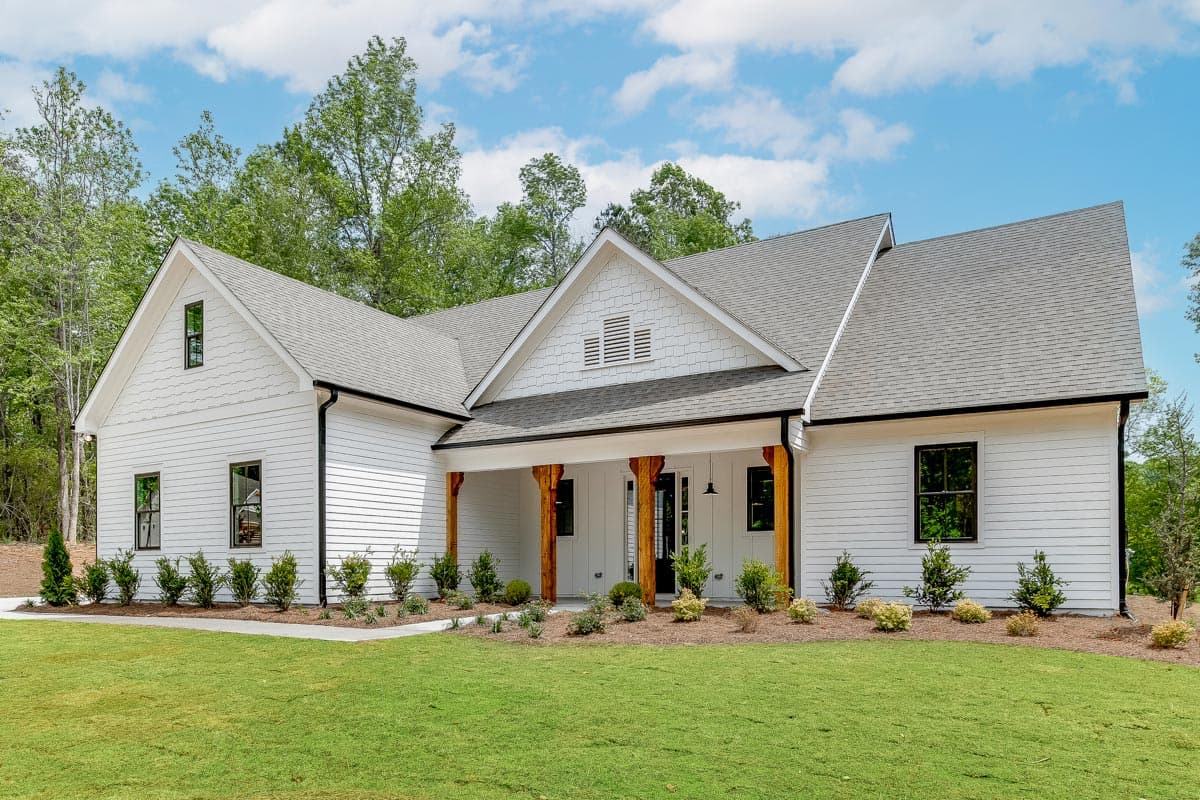 House plan exterior. Modern farmhouse style with gabled roof, prominent front porch with wood columns, and multiple dormers.