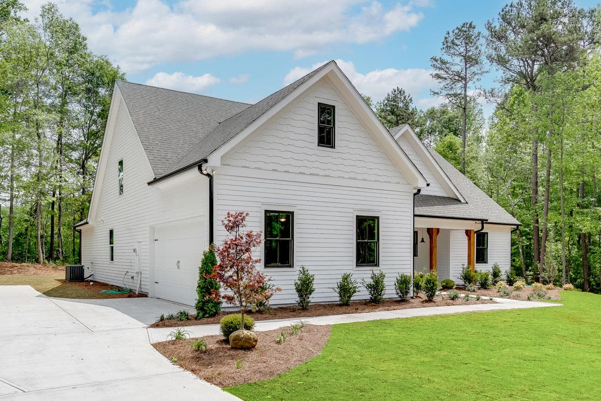 Modern Farmhouse house plan exterior with white lap siding, a gable roof, attached garage, and covered porch with wood posts.
