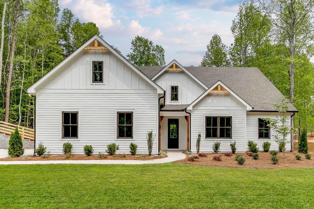 House plan exterior. Modern Farmhouse style with gabled roof, board-and-batten siding, and a covered porch entry with exposed beams.