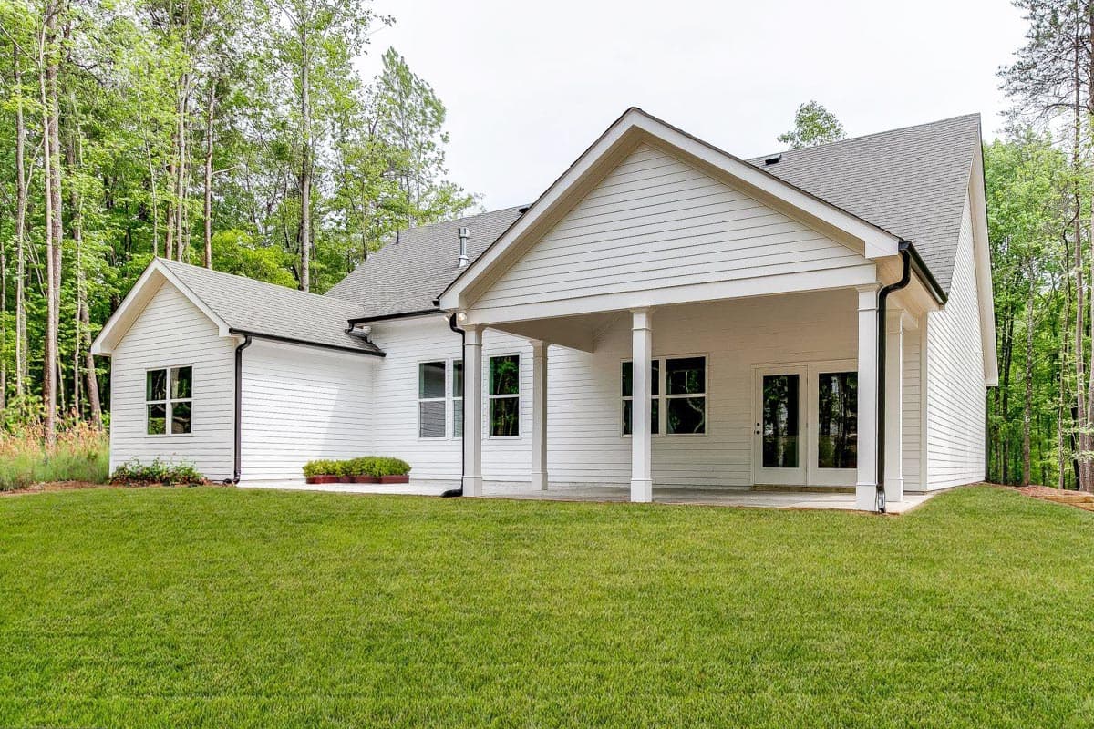 Modern Farmhouse house plan exterior with white siding, gabled roof, covered porch with columns, and double doors.