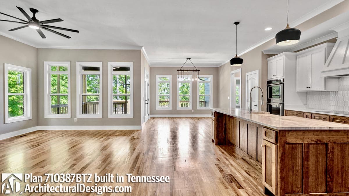 Open concept living area and kitchen with large island, wood floors, and multiple windows.