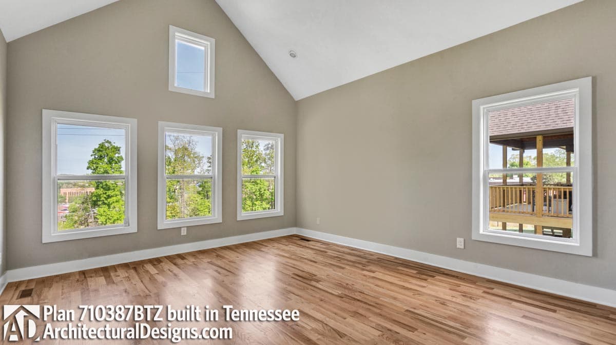 Interior view of room with vaulted ceiling, multiple windows, and wood floors.