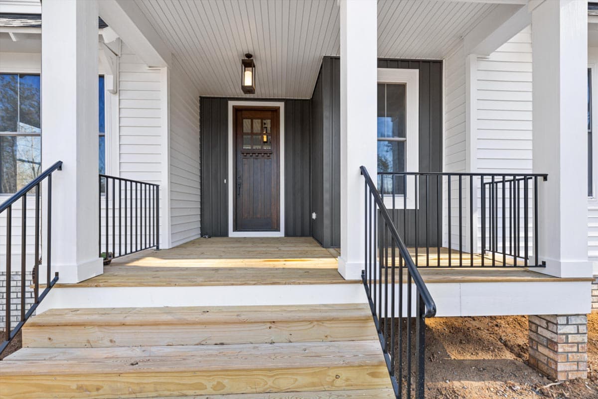 House plan exterior featuring a covered porch with wooden steps, a dark wood door, and white siding with dark vertical siding accents.