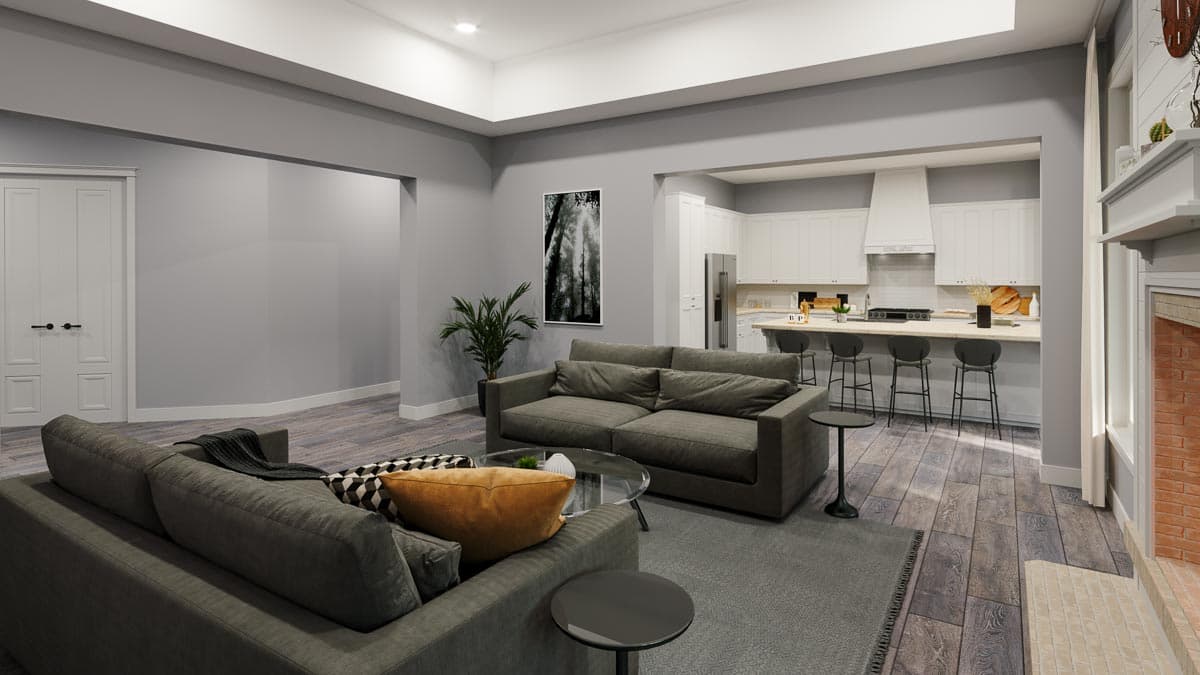 Living room with fireplace, open to kitchen with island and bar seating. Vaulted ceiling and double doors visible.