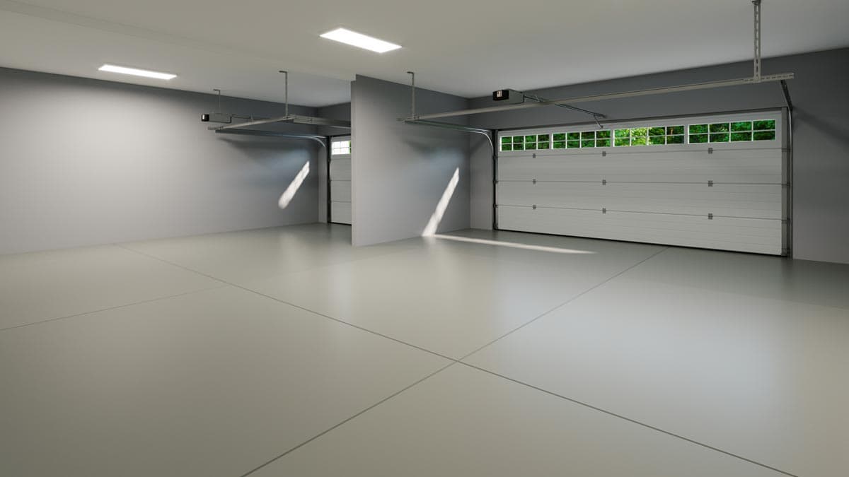 Interior view of a two-car garage with sectional doors, one open revealing windows and greenery.
