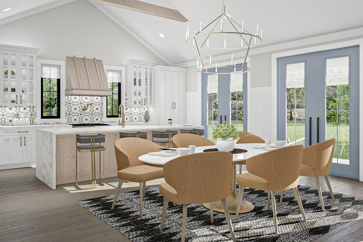 Open concept kitchen and dining area with vaulted ceiling, island with seating, and double doors to backyard.