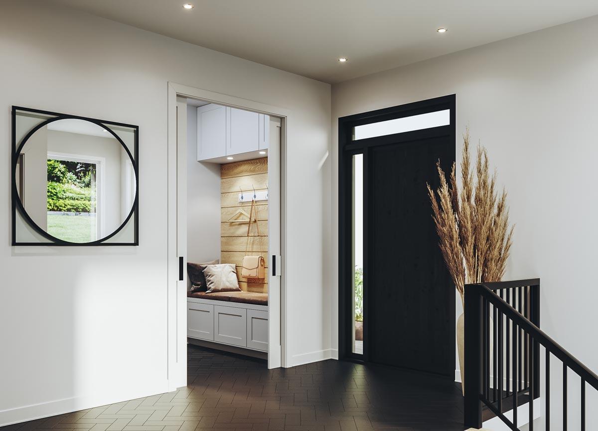 Interior view of a house entry with a bench, coat hooks, a modern black door with a sidelight, and a dark wood floor.