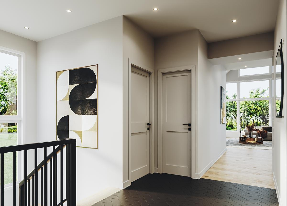 Interior hall with two doors, artwork, black railing, and view into a living room with large windows.