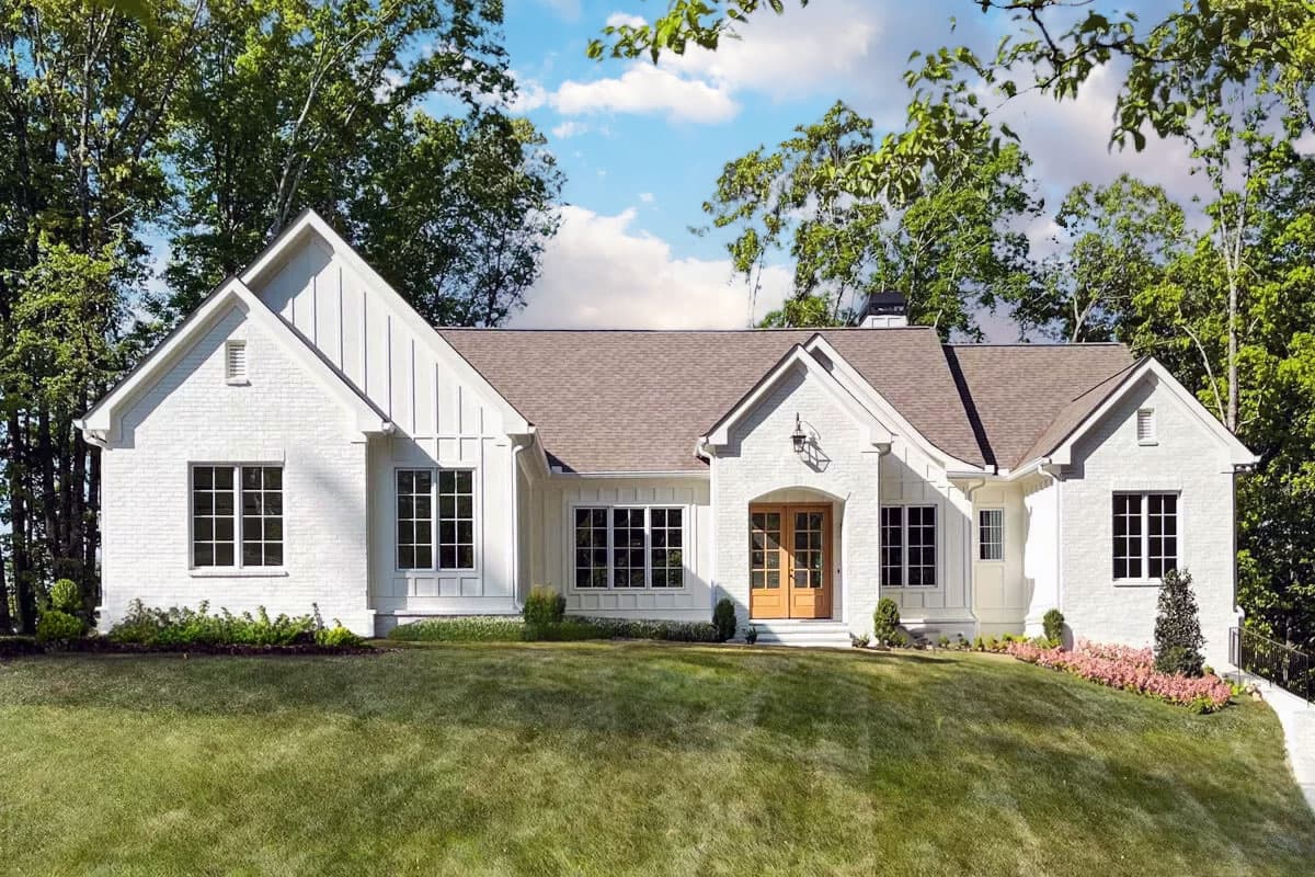 House plan exterior. One-story Modern Farmhouse with gables, a covered entryway with wood doors, and multiple multi-pane windows.