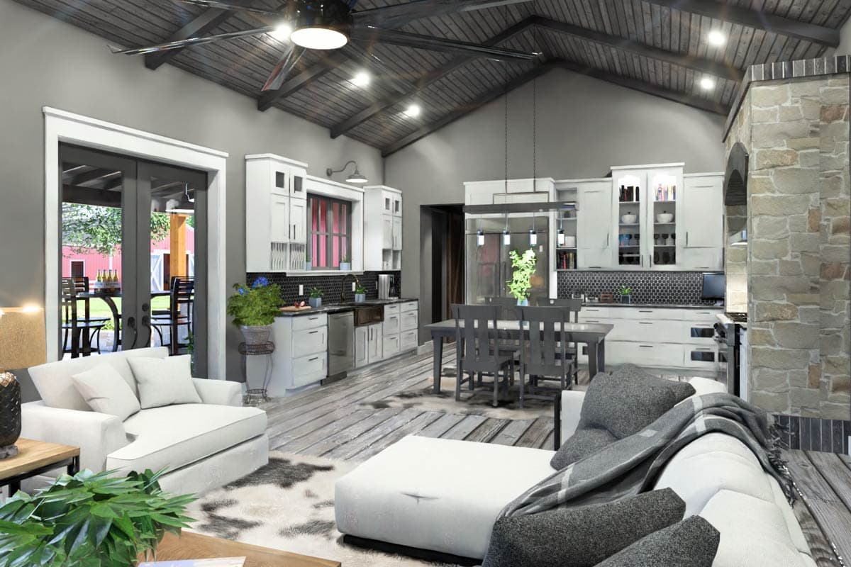 Open concept living and kitchen area with vaulted wood ceiling, white cabinets, island, and stone fireplace.