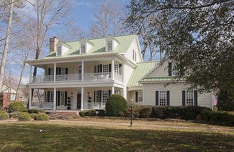 House plan exterior: two-story dwelling with wrap-around porches, dormers, and green metal roof.