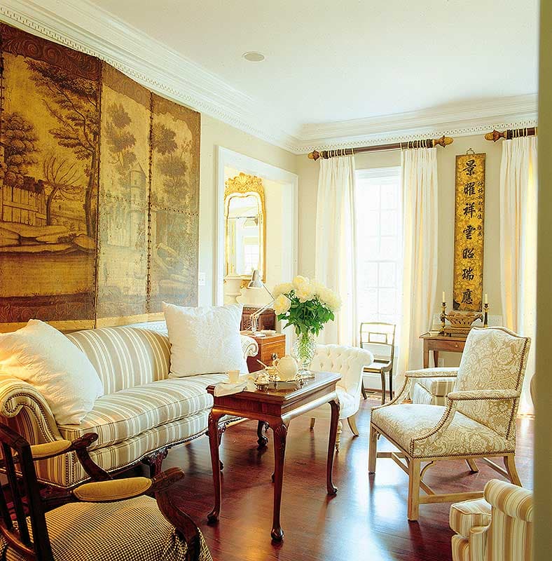 Living room with striped sofa, ornate chairs, decorative screen with landscape, and oriental calligraphy scrolls.
