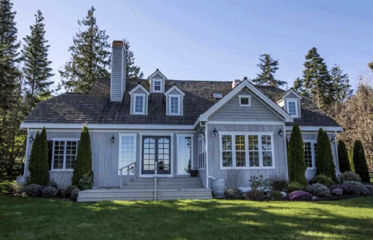 House plan exterior: Gray two-story home with multiple gables, dormers, a prominent chimney, and double entry doors.