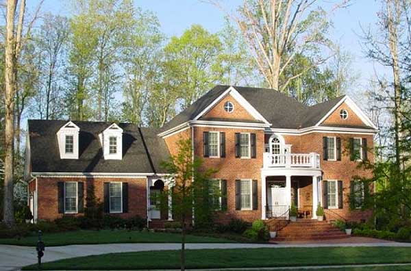 House plan exterior: brick two-story with dormer windows, gables, and a second-story balcony.