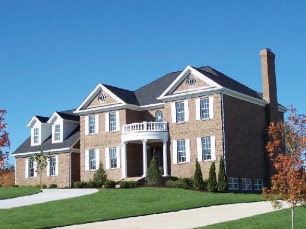House plan exterior of a two-story brick home with a central curved portico, dormers, and a prominent chimney.