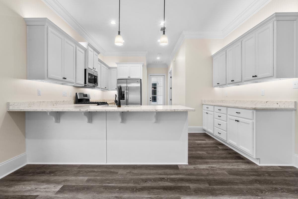 Kitchen featuring white cabinetry, granite countertops, stainless steel appliances, and a center island with a breakfast bar.