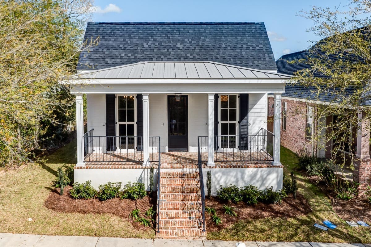 House plan exterior. One-story Cottage style with a front porch, metal roof over porch, brick steps, and shutters flanking windows.