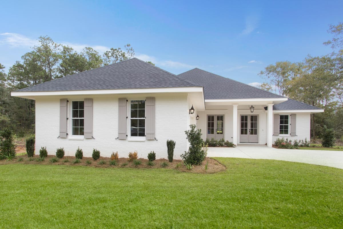 House plan exterior: Single-story white brick home with gray shutters, hip roof, and covered double entry.