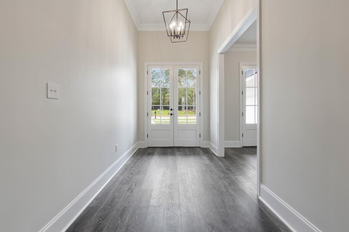 Interior view of entryway with double glass doors, dark wood flooring, and modern geometric chandelier.
