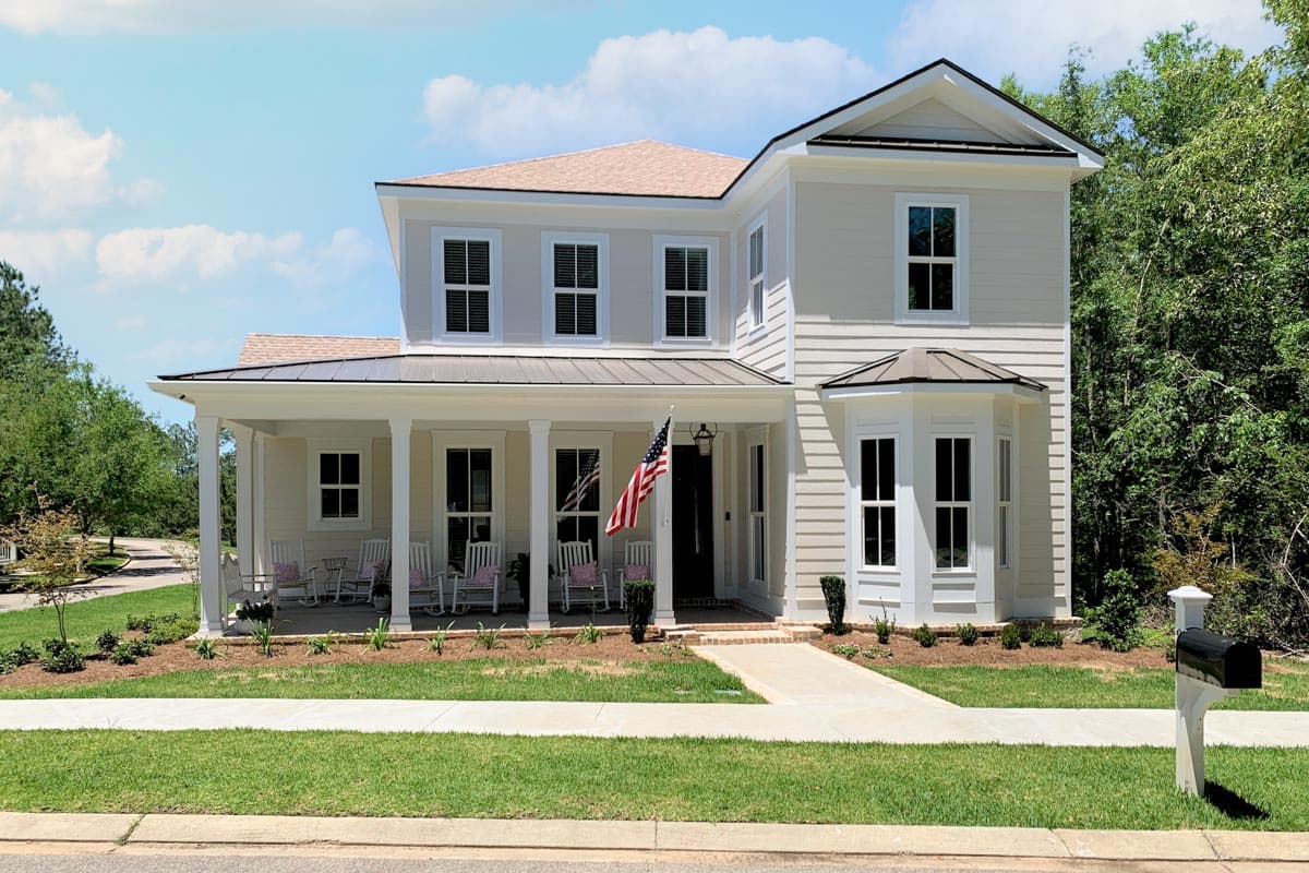 House plan exterior of a two-story home with a wraparound porch, bay window, and multiple gables.