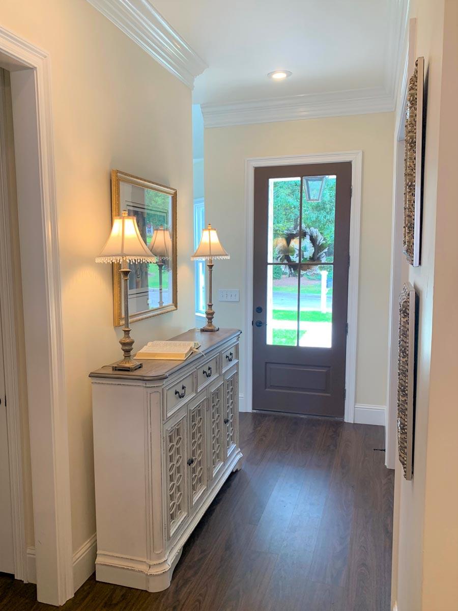 Interior view of a hallway with a decorative console table and a glass-paneled door with a wreath.