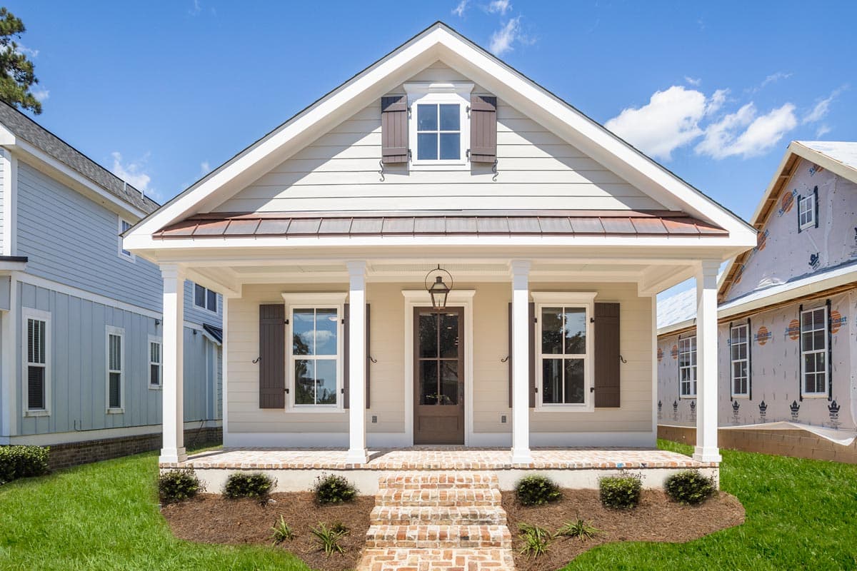 House plan exterior featuring a cottage style with a front porch, gables, and decorative shutters on the windows. One story home.