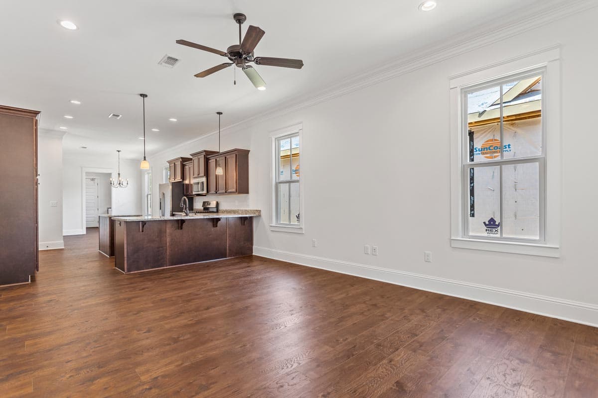 Open-concept living space with island kitchen, dark wood cabinets, and dark wood flooring.