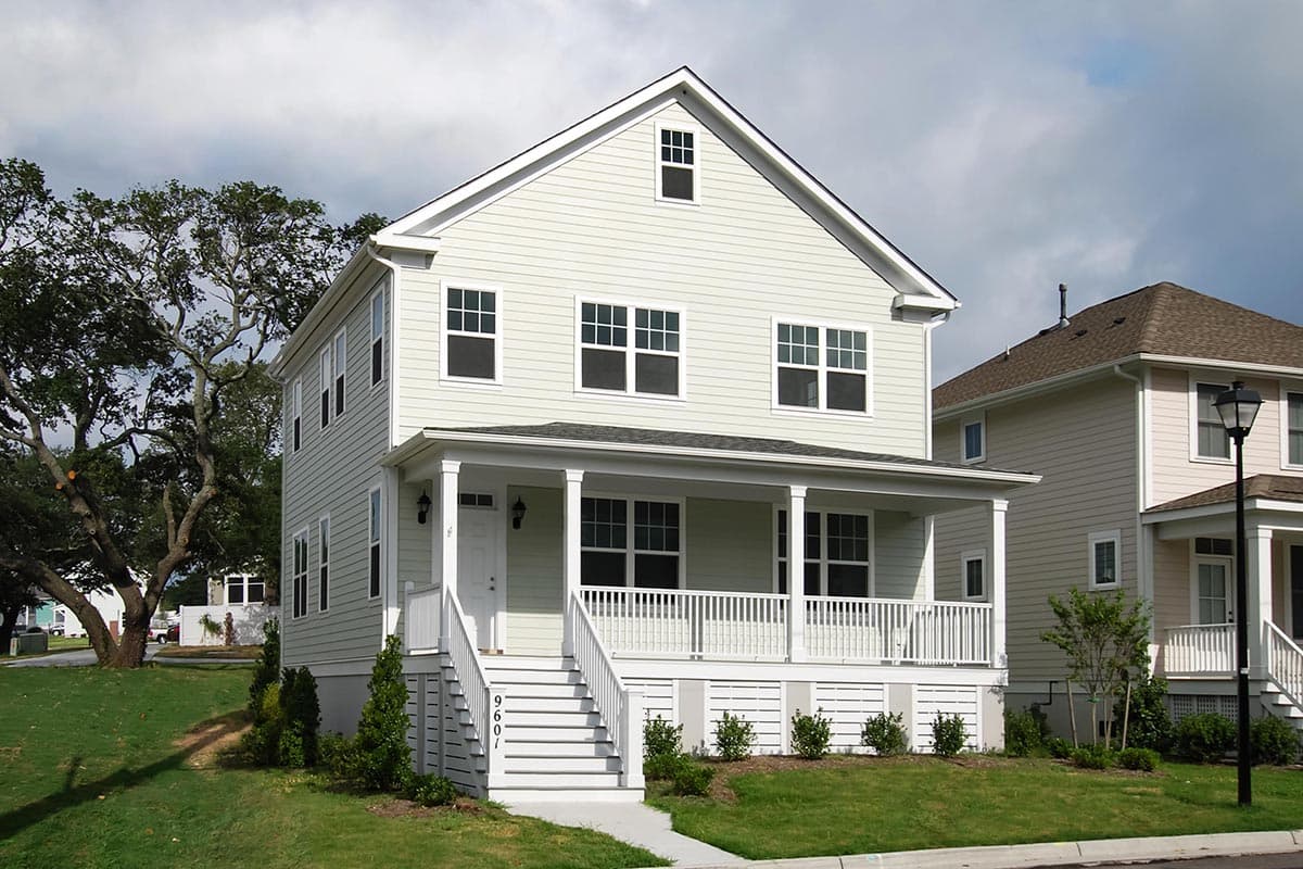 House plan exterior. Two-story house with front porch, gabled roof, and dormer. Features include a symmetrical façade and a columned porch.