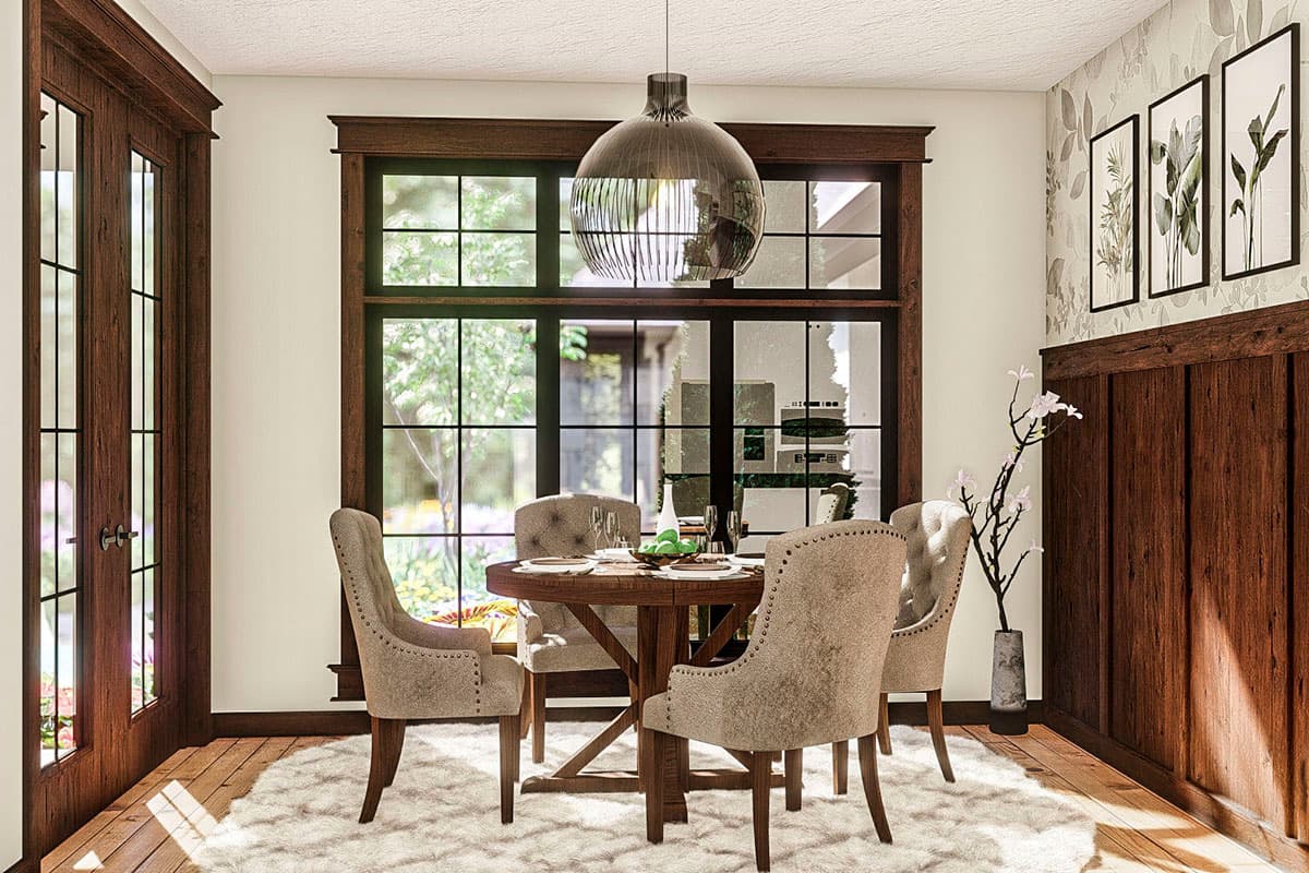 Dining room with round table, upholstered chairs, large gridded window, and paneled wood wall.