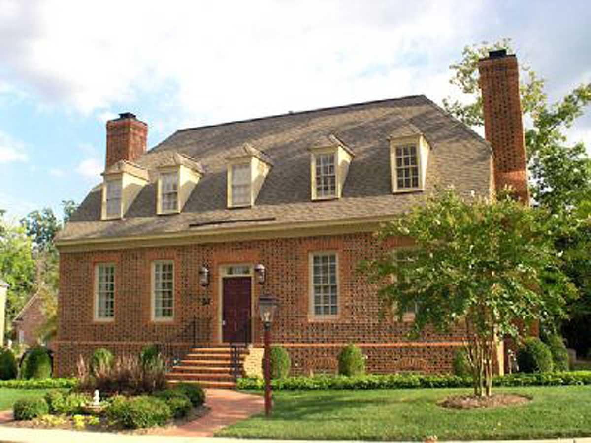 Two-story brick house plan with prominent chimneys, five dormer windows, and a central covered entryway with brick steps.