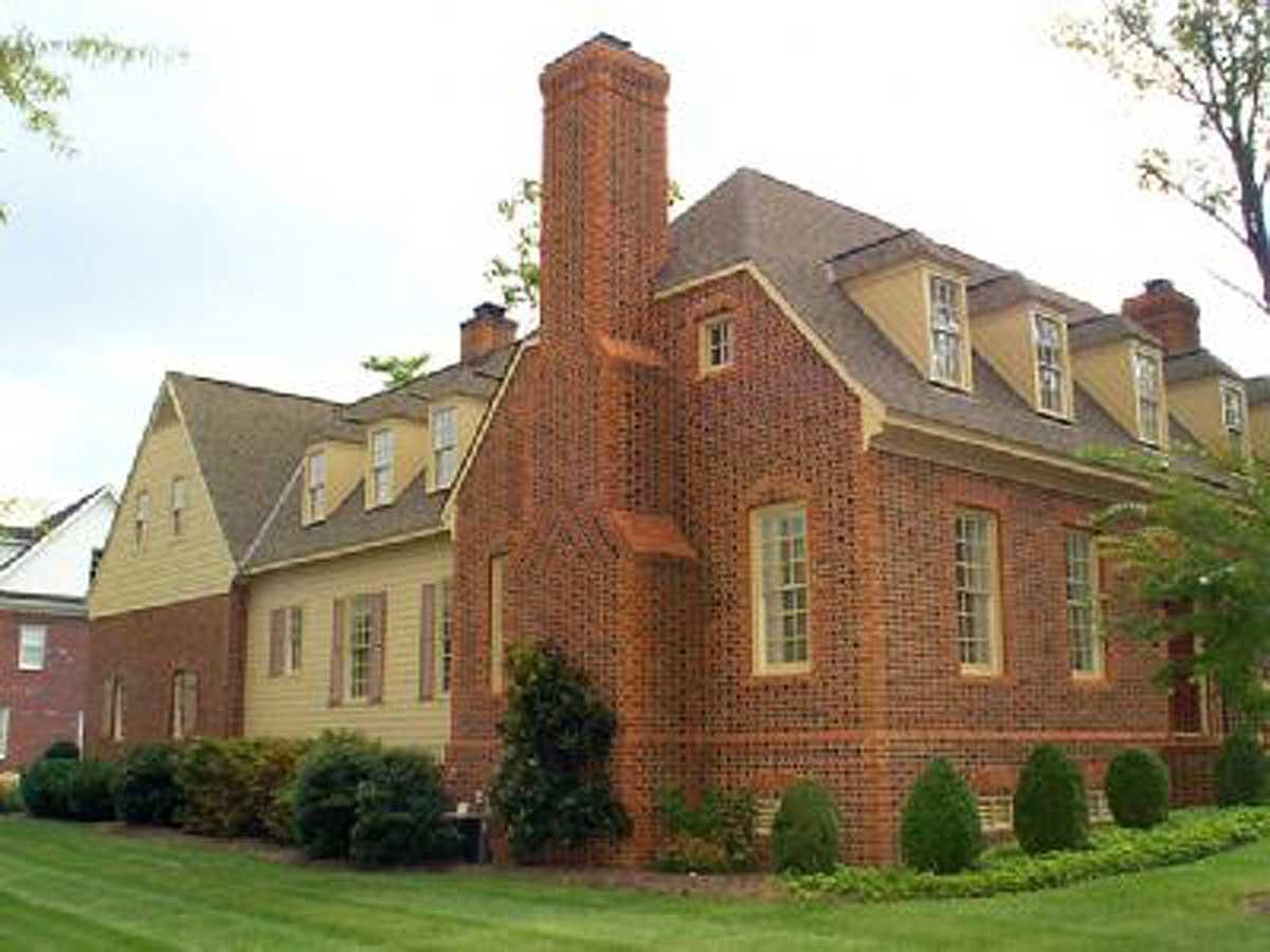 House plan exterior: brick structure with side gables, multiple dormers, and a prominent brick chimney.