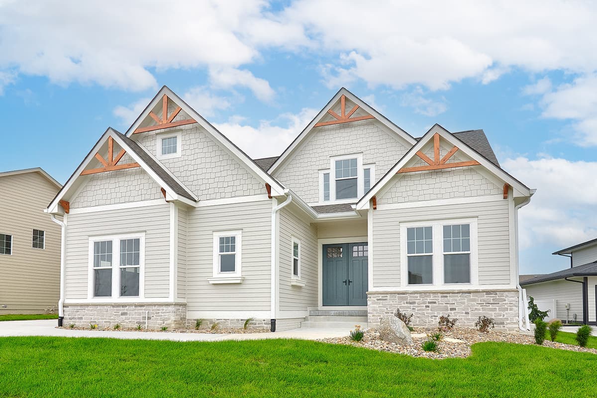 House plan exterior: Ranch style with gables, decorative trusses, stone and shingle siding, and double front doors.