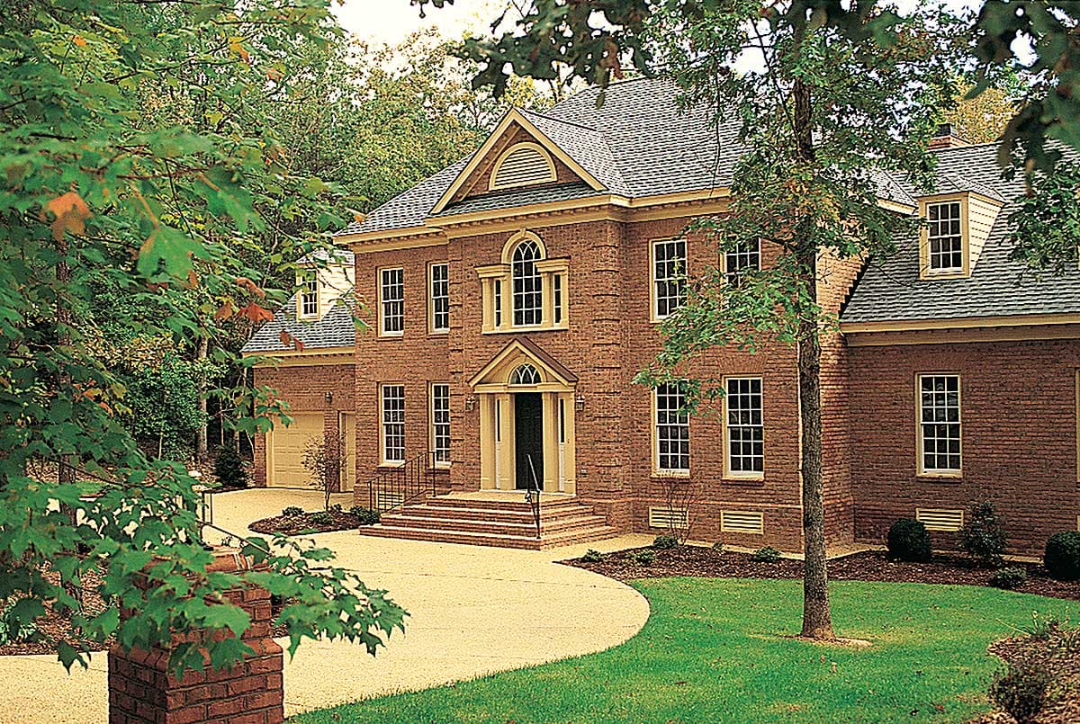 Traditional brick house plan exterior with central gable, arched windows, portico entry, dormers, and attached garage.