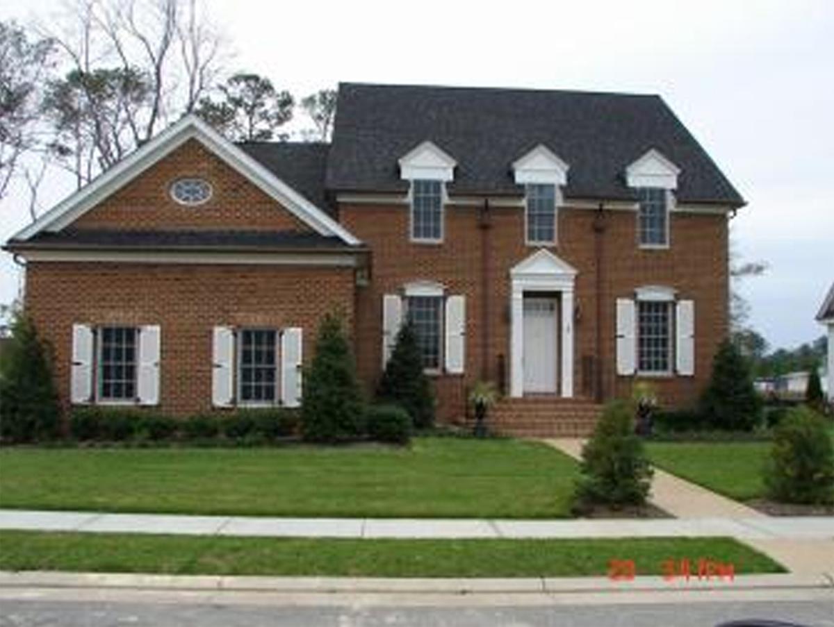Two-story brick house plan with a symmetrical facade, white shutters, dormer windows, and a prominent front entrance.