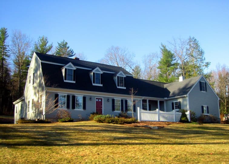 House plan exterior of a two-story Colonial Revival home with dormers, a gambrel roof, and a front porch with white picket railing.