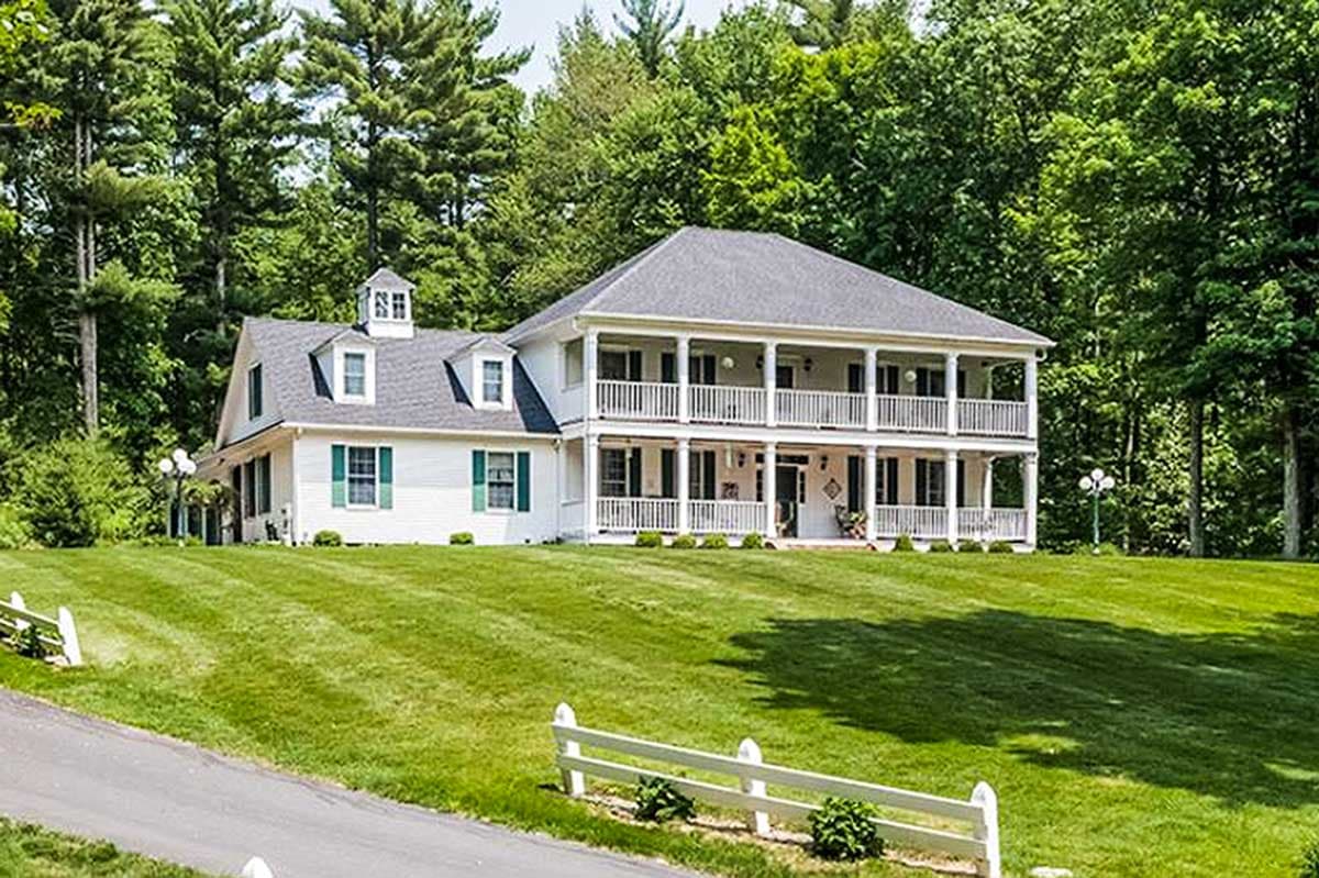 House plan exterior: two-story home with a double wraparound porch, dormers, and a cupola.