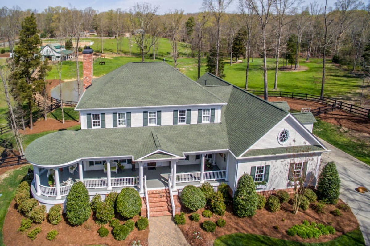 House plan exterior: Two-story home with wrap-around porch, dormers, and a prominent brick chimney.