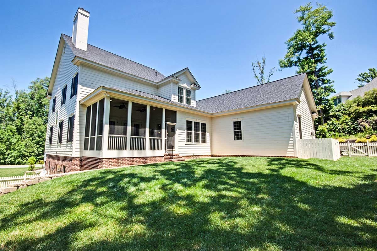 House plan exterior featuring a two-story structure with a screened porch, gable dormer, and brick foundation.