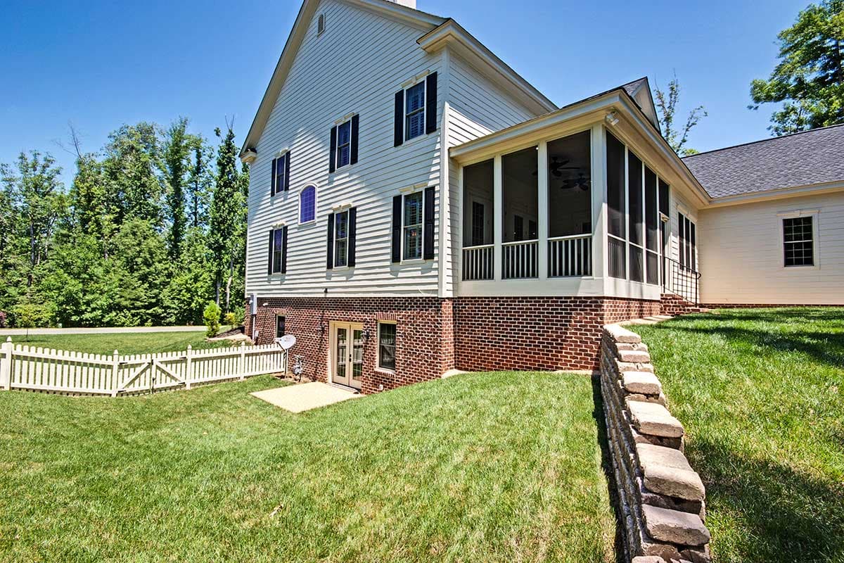 House plan exterior: Two-story home with white siding, brick foundation, screened porch, gables, and dormers.