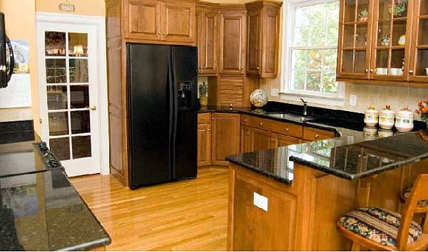 Kitchen featuring wood cabinetry, granite countertops, black refrigerator, and glass-paneled door.